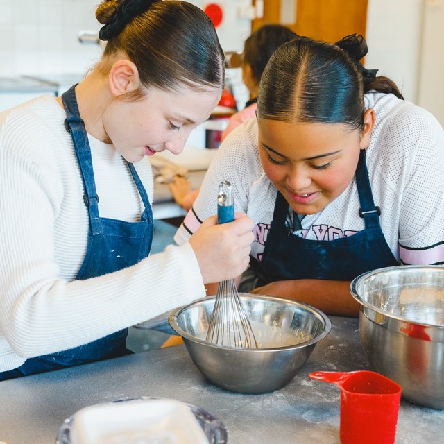 Two young students whisking a mixture together in a cooking class