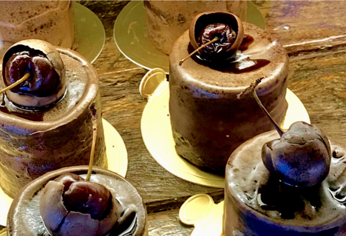 Little chocolate mousse cakes, each topped with a glazed cherry