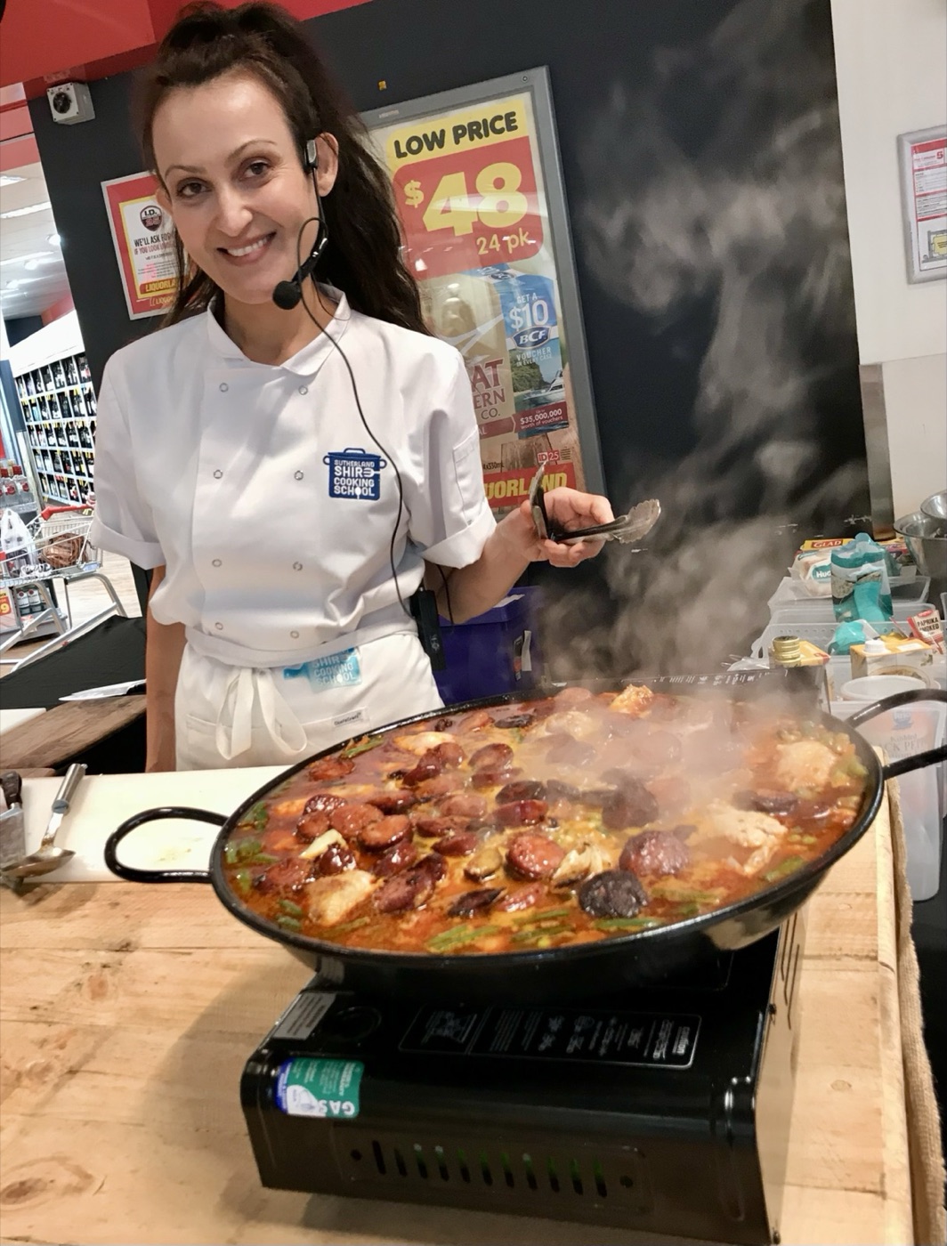 Yvonne smiling in her chef whites during a paella demonstration