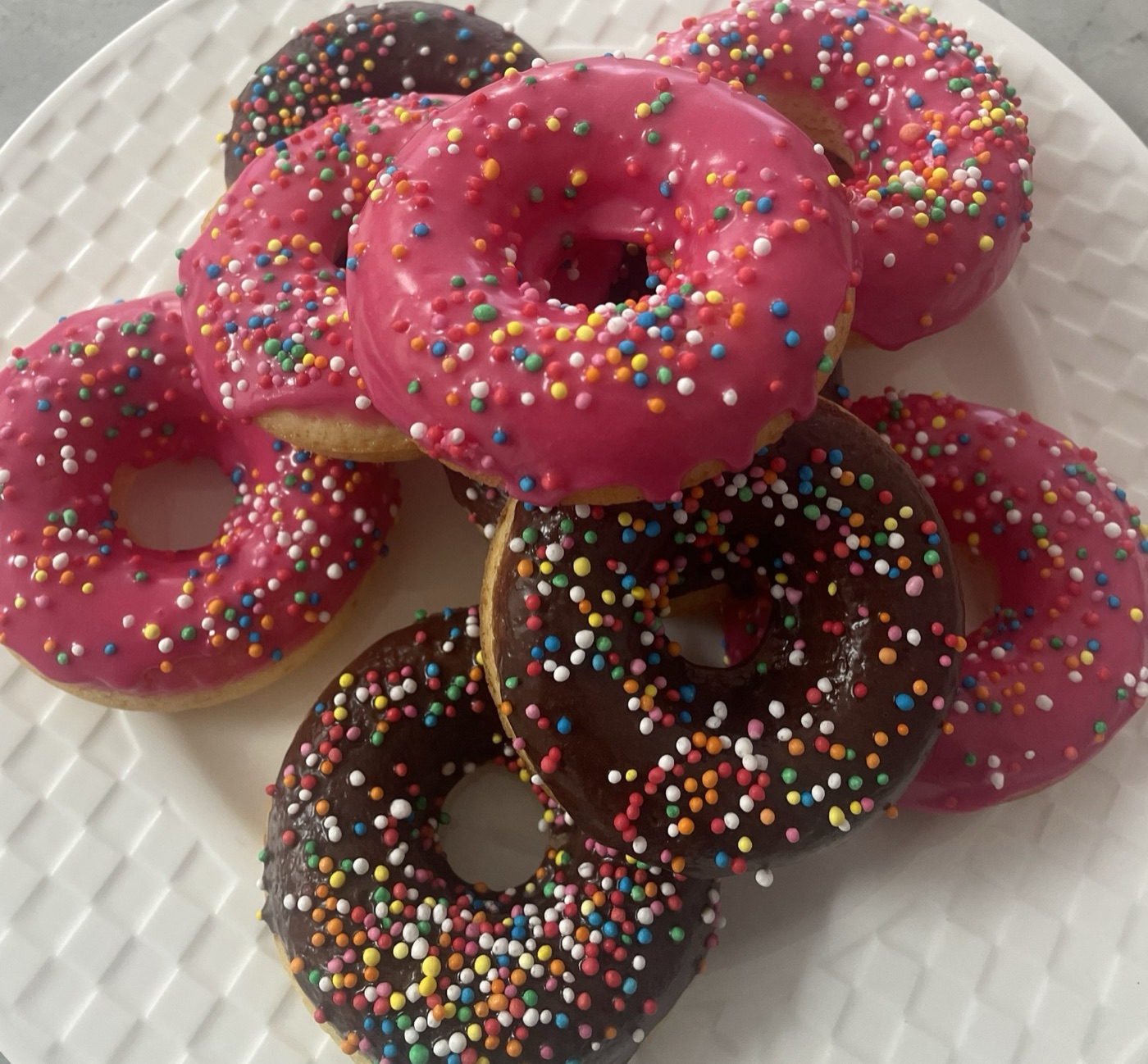 Pink and chocolate glazed doughnuts covered in sprinkles