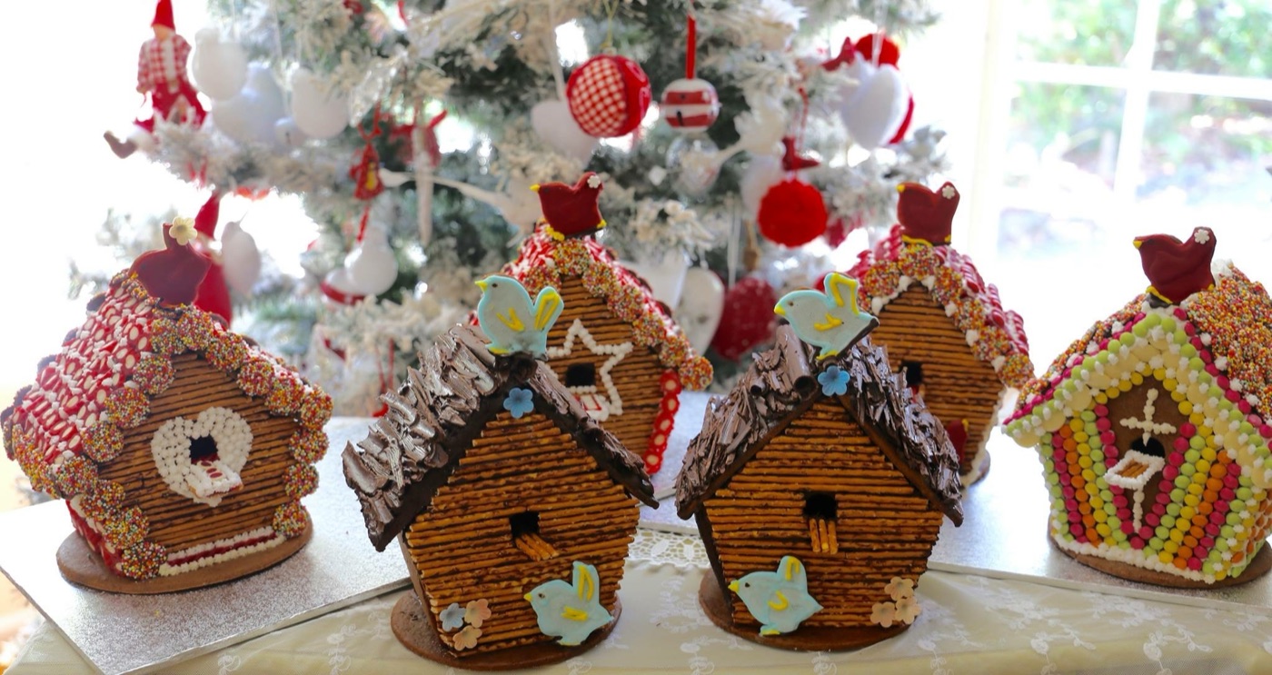 Gingerbread birdhouses in front of a Christmas tree
