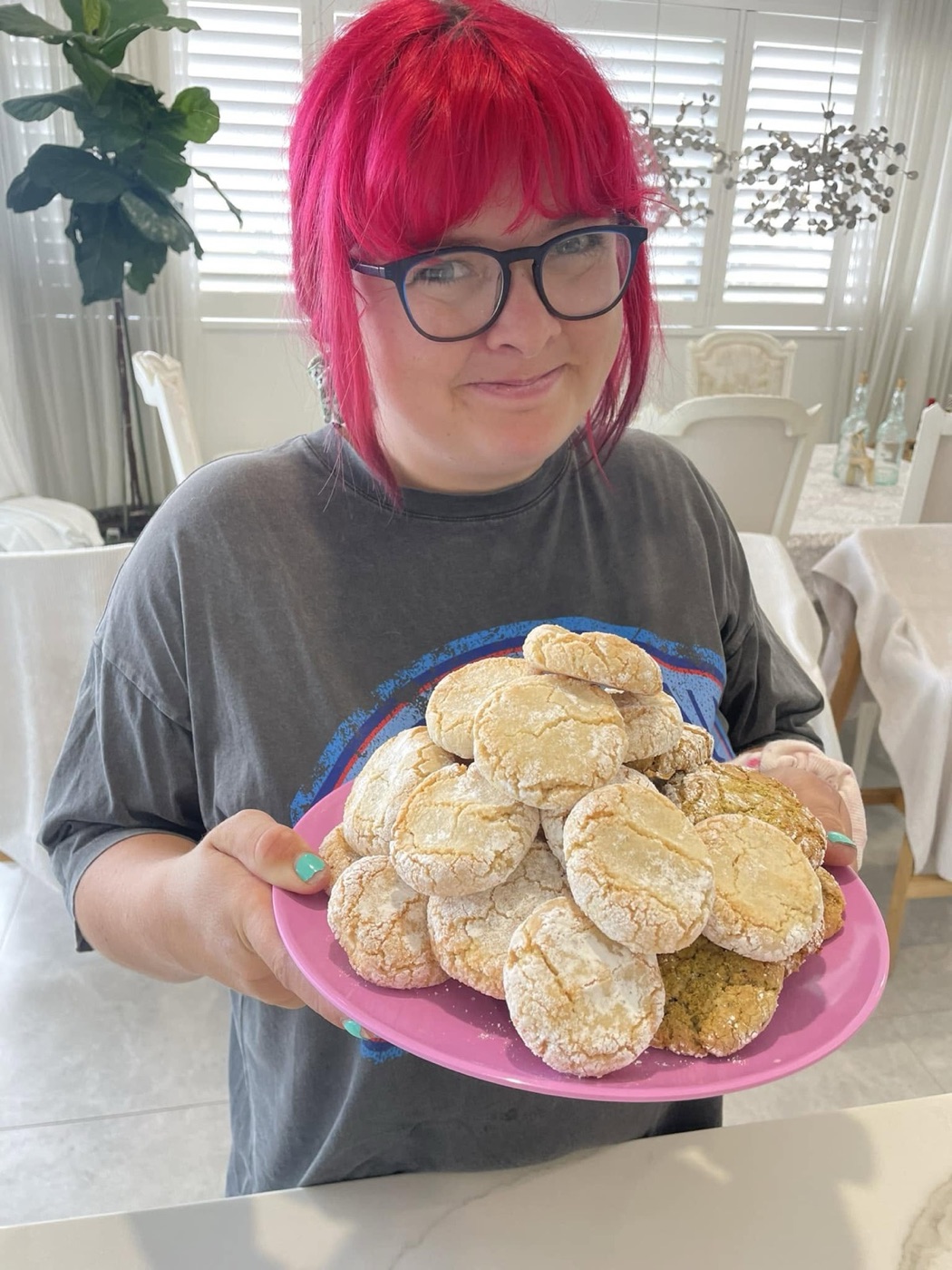 A proud baker holding a plateful of golden amaretti cookies