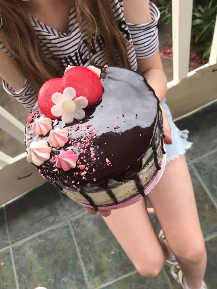 A chocolate drip cake topped with macarons and meringue kisses