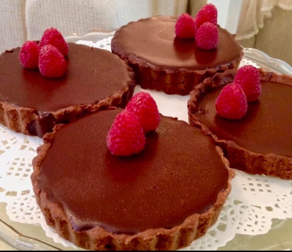 Chocolate ganache tarts, each crowned with fresh raspberries