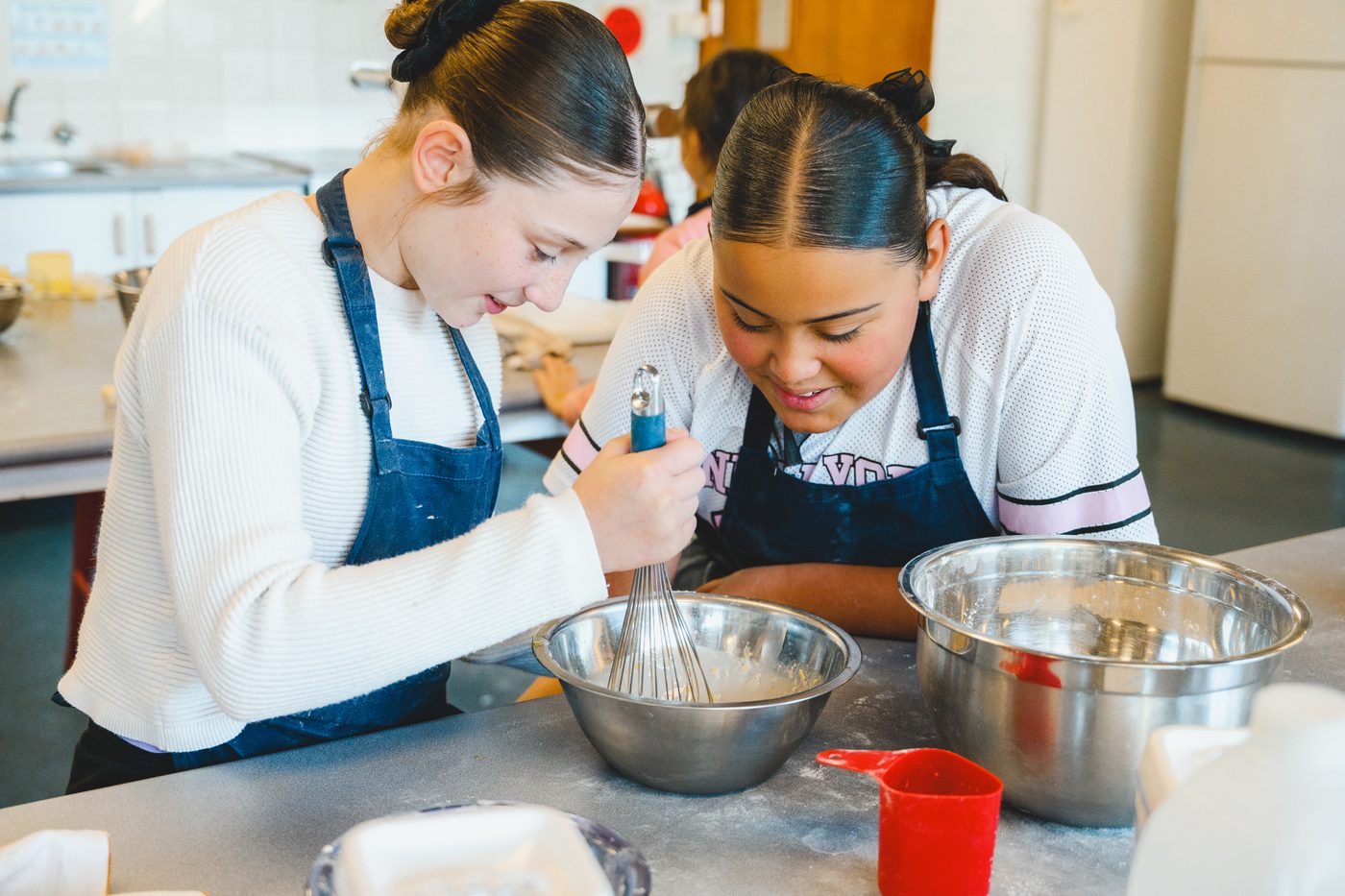 Two students at the bench preparing their mix, piping bag at the ready