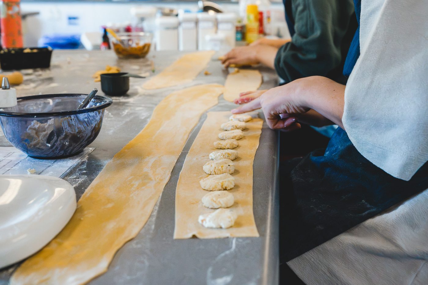 Spaced dollops of filling running down a long pasta strip, ready to fold