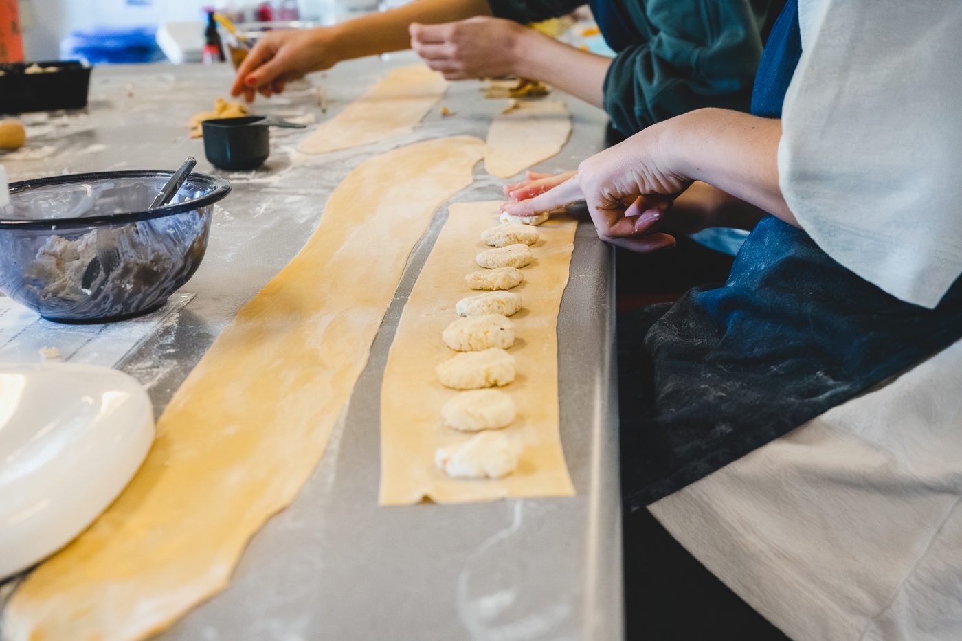 Spoonfuls of ricotta filling laid along a pasta sheet, ready to be folded into ravioli