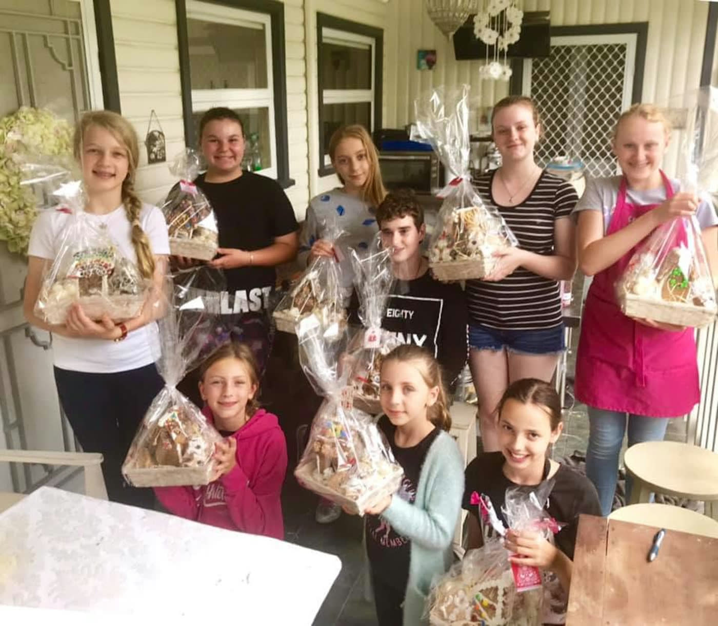 The class holding up their finished gingerbread houses, each bagged and ribboned