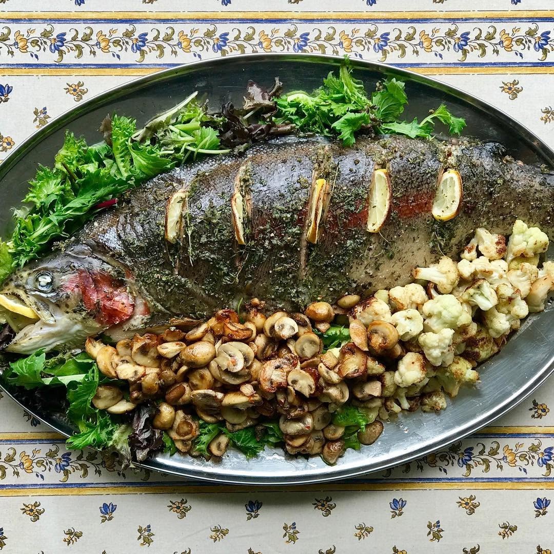 A whole baked salmon studded with lemon, with mushrooms and roasted cauliflower